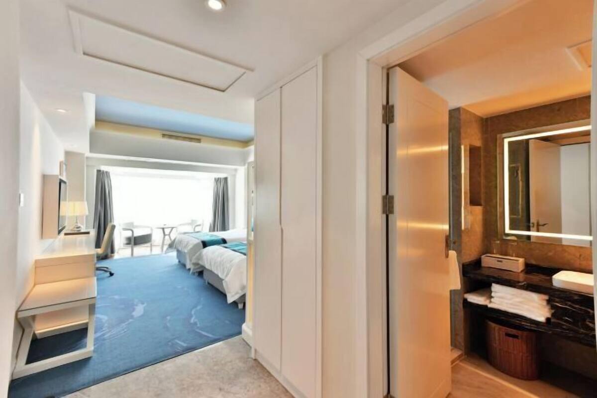 Ein Hotelzimmer mit Bett, Schreibtisch, Stuhl und einem Badezimmer mit Spiegel, mit Blick ins Freie.