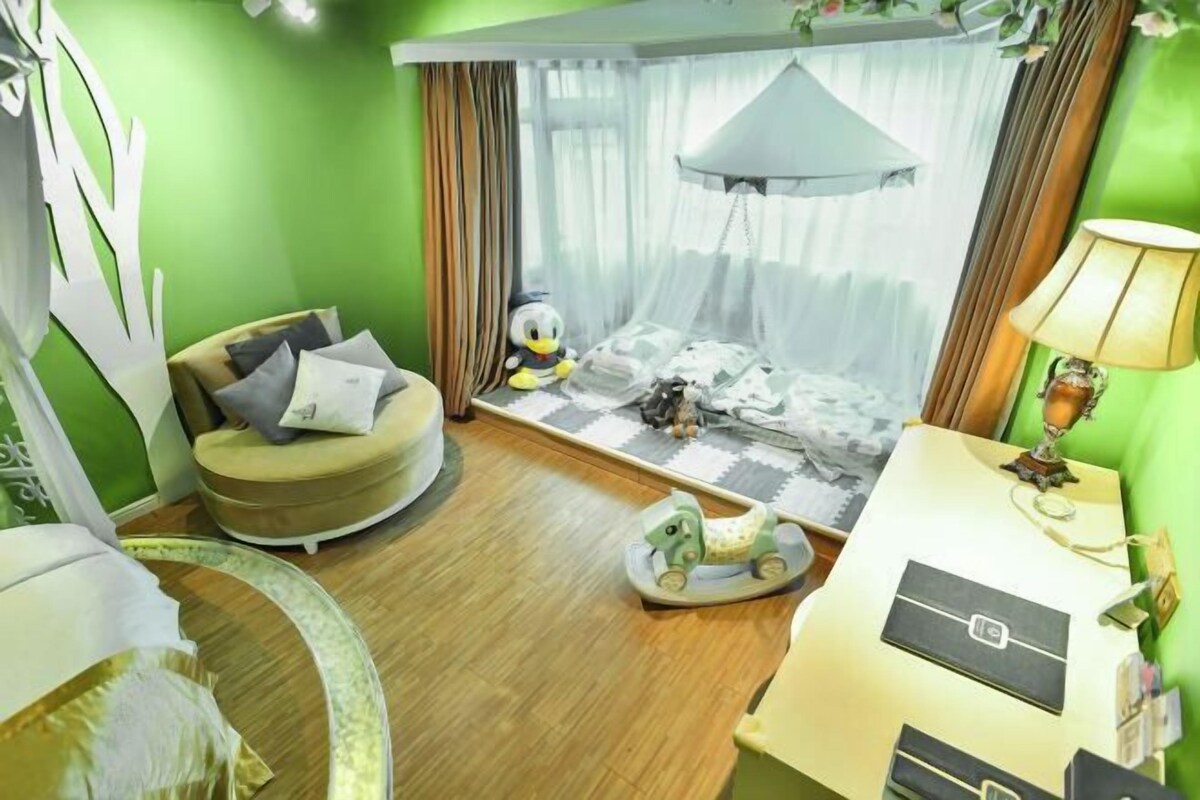 A room with a bed, a chair, a small table, a lamp, and a window with curtains.