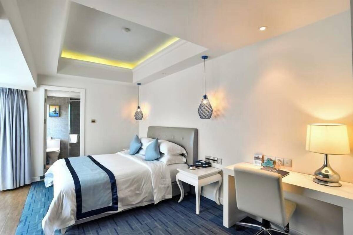 Ein modernes Hotelzimmer mit Bett, Nachttisch, Schreibtisch und Lampe.