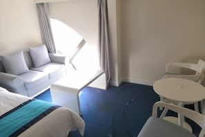 A hotel room with a bed, a sofa, a small table, and a chair.