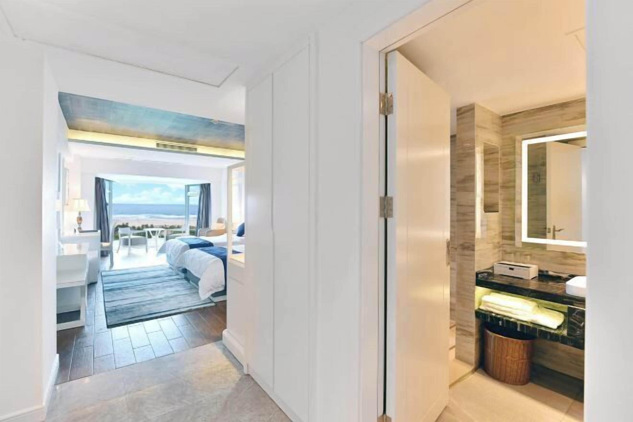 A hotel room with a bed, bedside table, and a view of the sea.