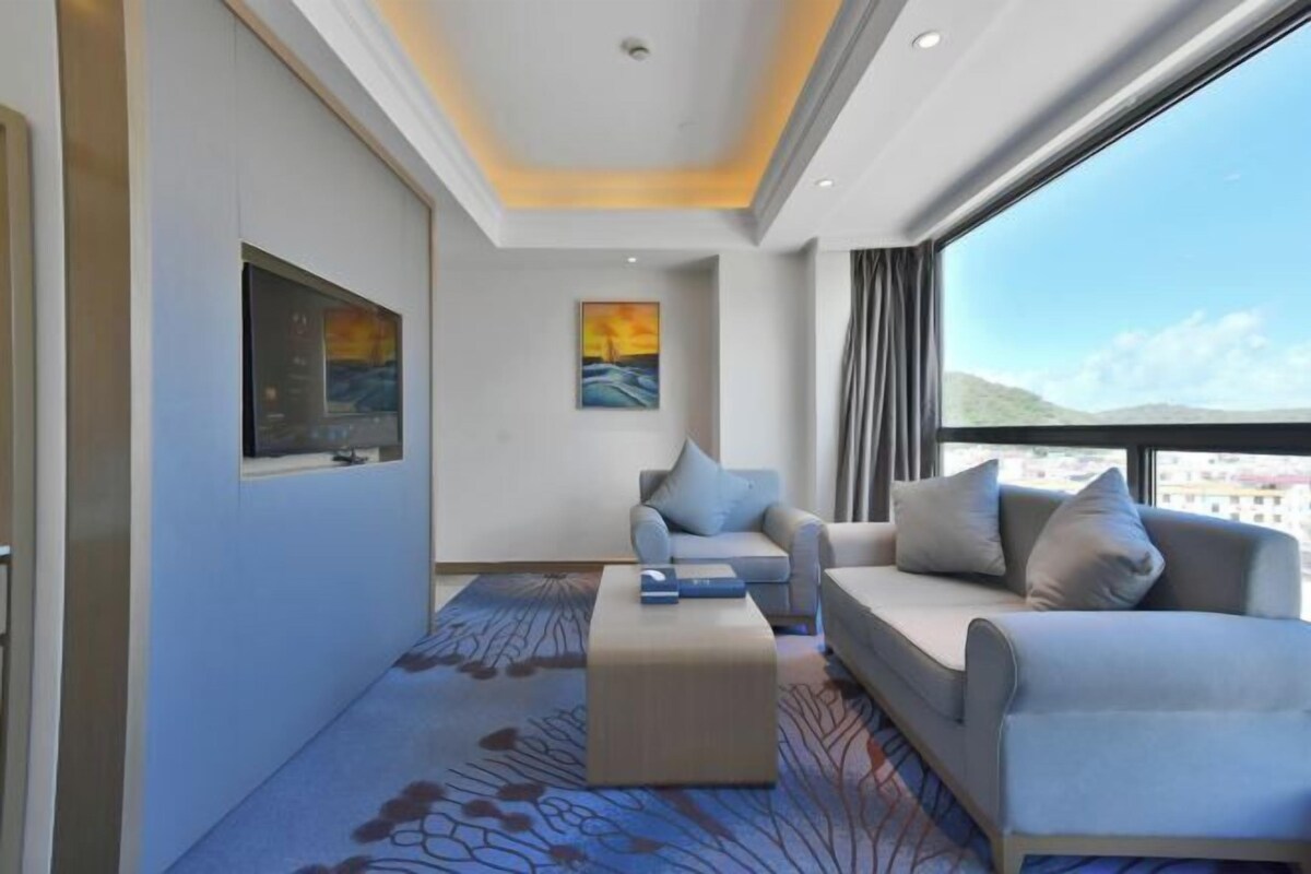 A modern hotel room with a sofa, a coffee table, and artwork on the walls.