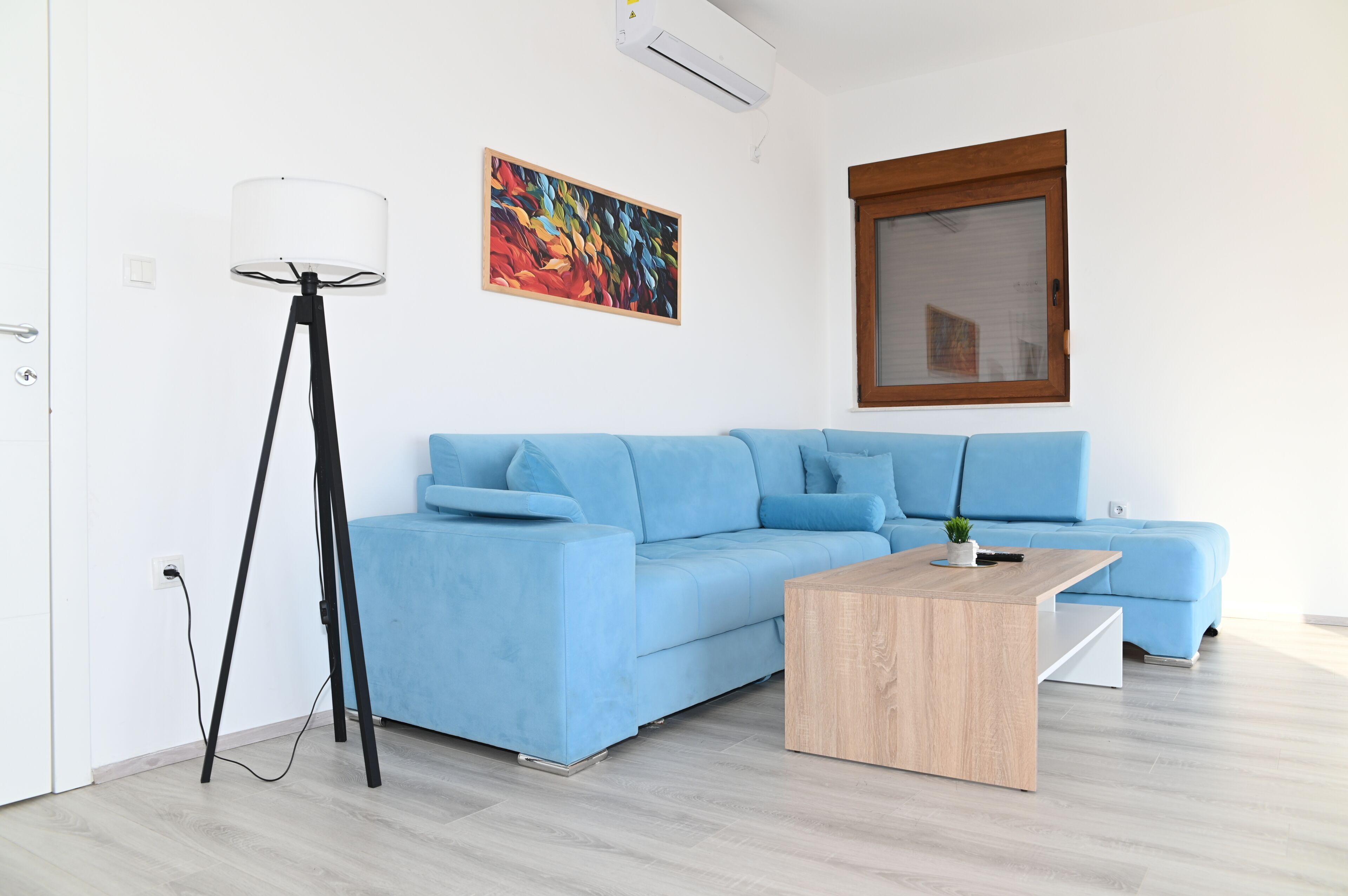 Ein modernes Wohnzimmer mit einem hellblauen Sofa, einem Holztisch und einer Stehlampe.