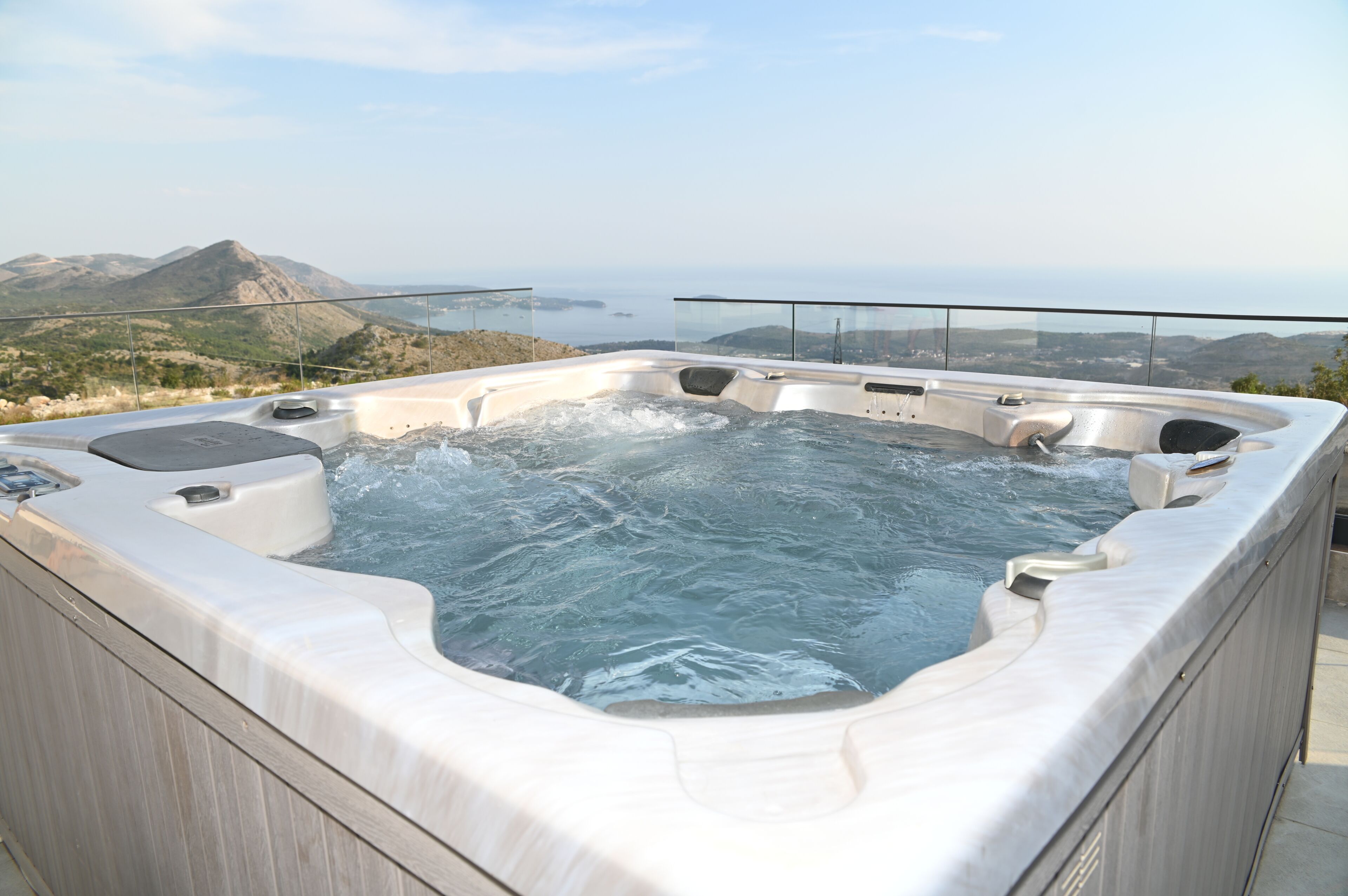 Un jacuzzi con vistas panorámicas de un paisaje montañoso y el mar.