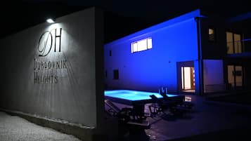 Ein Gebäude mit einem Schild, auf dem "Dubrovnik Heights" steht, und einem Poolbereich mit Liegestühlen.