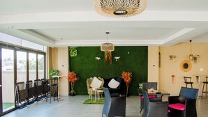 Una habitación amplia con una pared verde, un sofá y varias sillas.