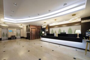 A hotel reception area with a modern design, featuring a reception desk, a counter, and a seating area. - Wings Hotel(East Railway Station Sports Institute Branch) (Guangzhou)