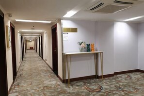 Un couloir d’hôtel avec un sol recouvert de moquette, un comptoir de réception et un panneau sur le mur.