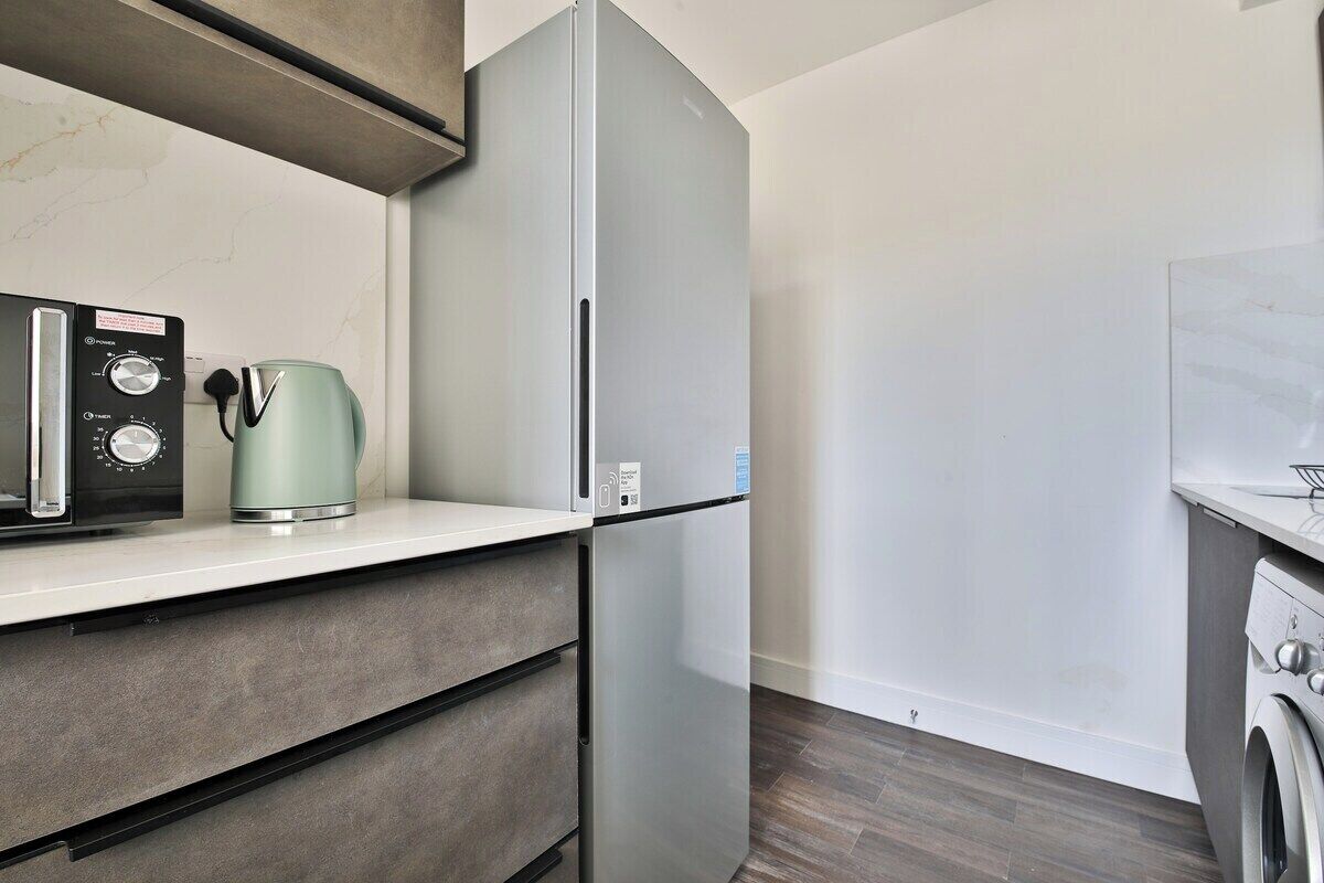 A modern kitchen with a built-in refrigerator, a coffee maker, and a washing machine.
