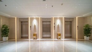 A spacious lobby with a polished marble floor, three elevators, and potted plants. - Zhucheng Huaxi Grand Hotel (Zhucheng)