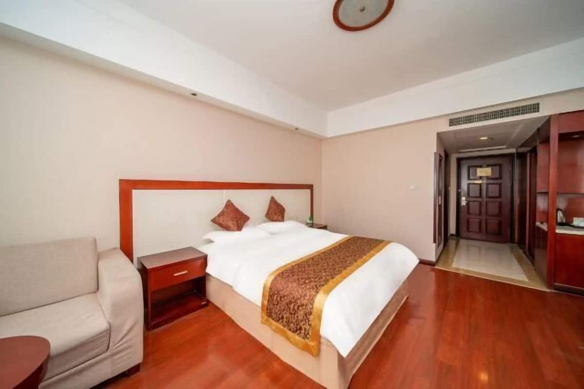 Ein Hotelzimmer mit einem großen Bett, einem Nachttisch, einer Couch und Holzboden.
