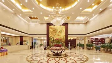 A spacious lobby with a central floral arrangement, a chandelier, and a reception desk.