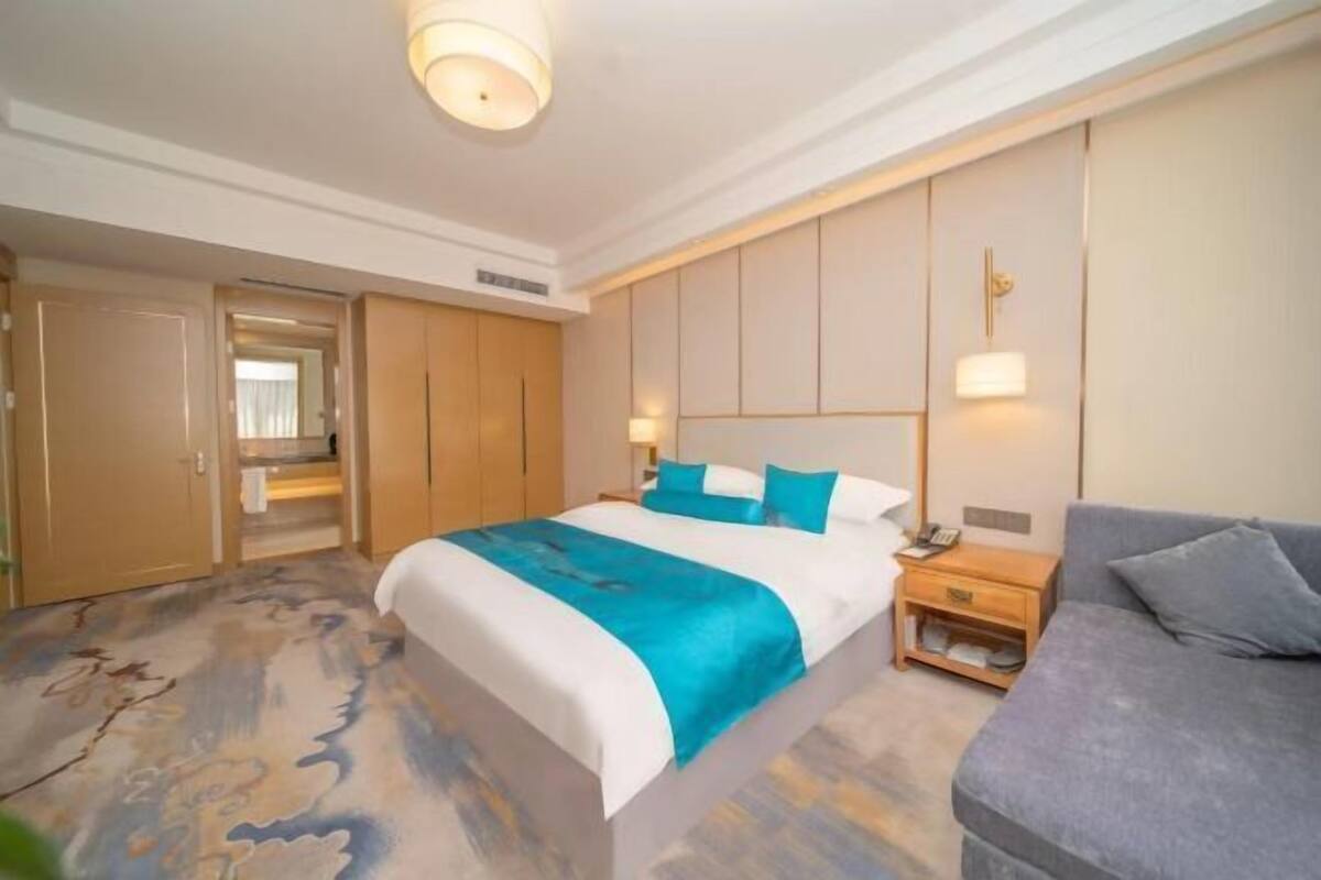 Ein Hotelzimmer mit Bett, Nachttisch, Sofa und Kleiderschrank.