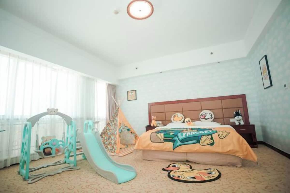 Ein Schlafzimmer mit Bett, einem Spielbereich mit Rutsche und einem Zelt.