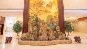 A traditional Chinese landscape painting in a wooden frame, surrounded by a rock garden with two potted trees. - Zhucheng Huaxi Grand Hotel (Zhucheng)