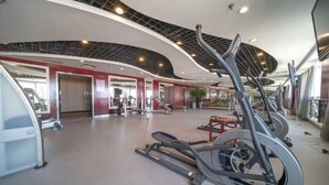 A modern gym with treadmills, weight machines, and a curved ceiling design. - Zhucheng Huaxi Grand Hotel (Zhucheng)