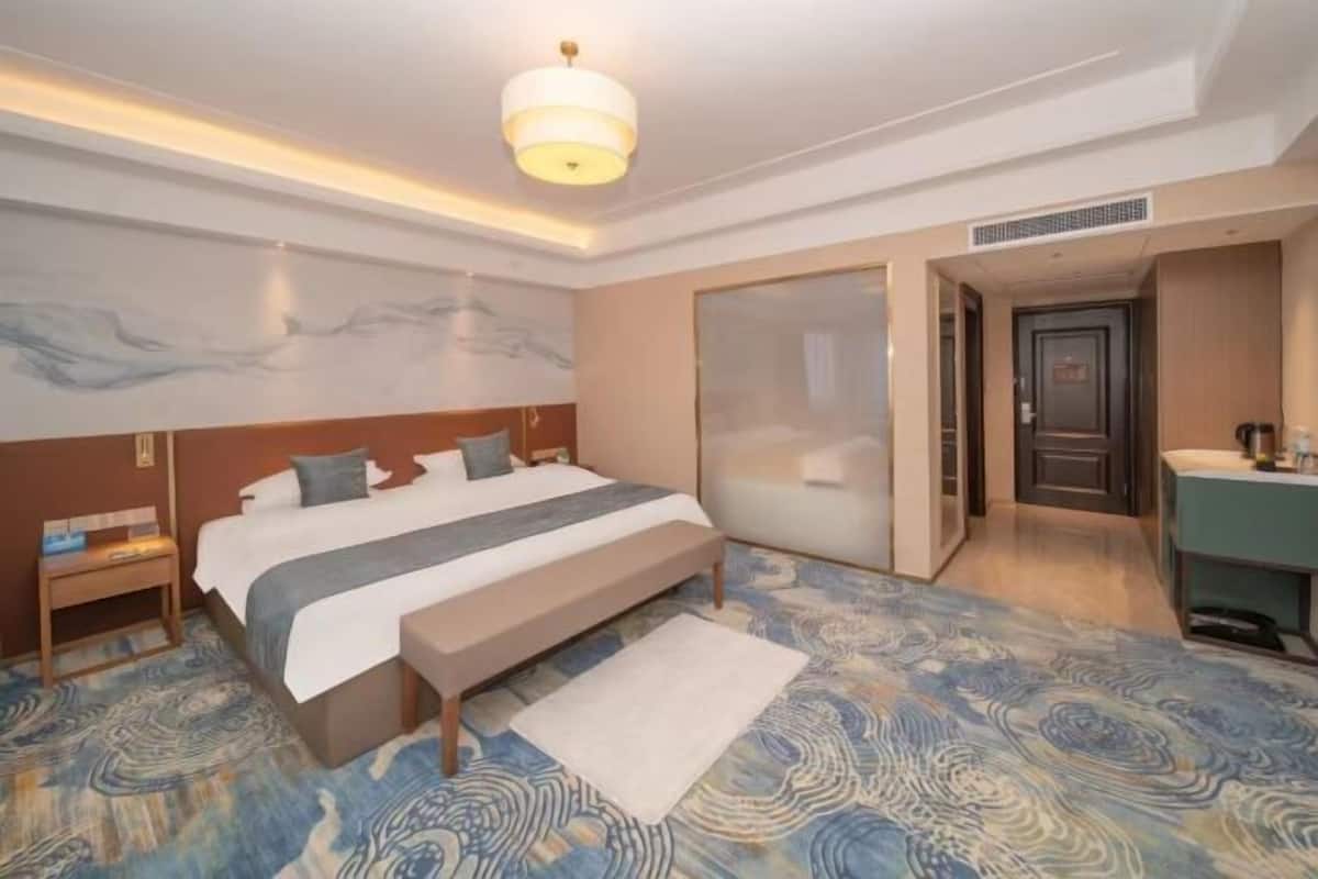 Ein Hotelzimmer mit Bett, Nachttisch und einem großen Fenster.