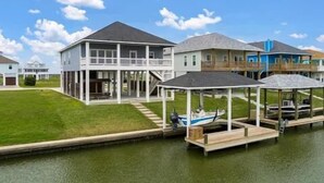 A waterfront property with a large house featuring a covered porch and a boat dock. - Boaters' paradise, direct access to the Intracoastal, East Bay and Gulf. (Bolivar Peninsula)