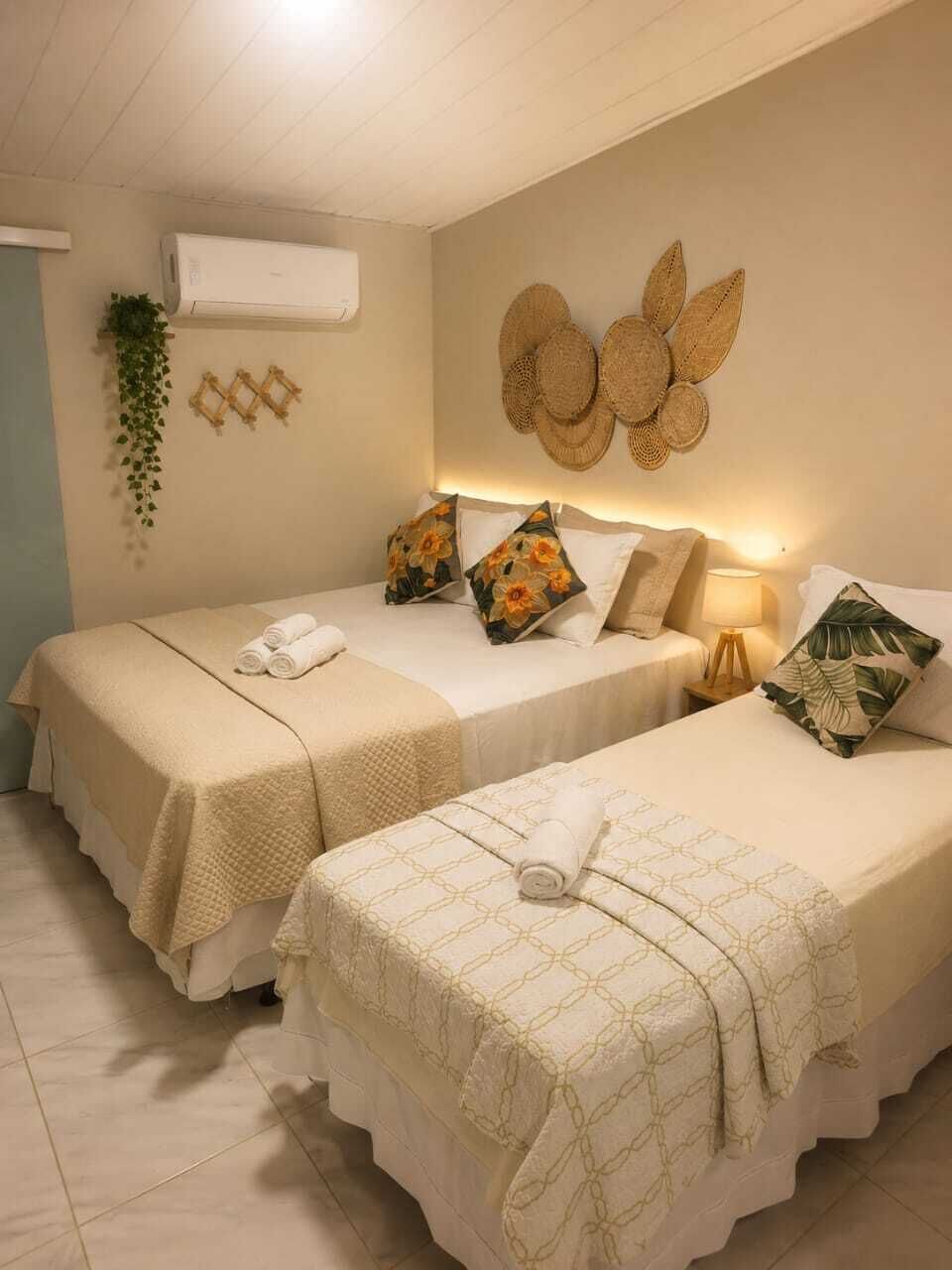A hotel room with two beds, a wall-mounted air conditioner, and a decorative wall piece.