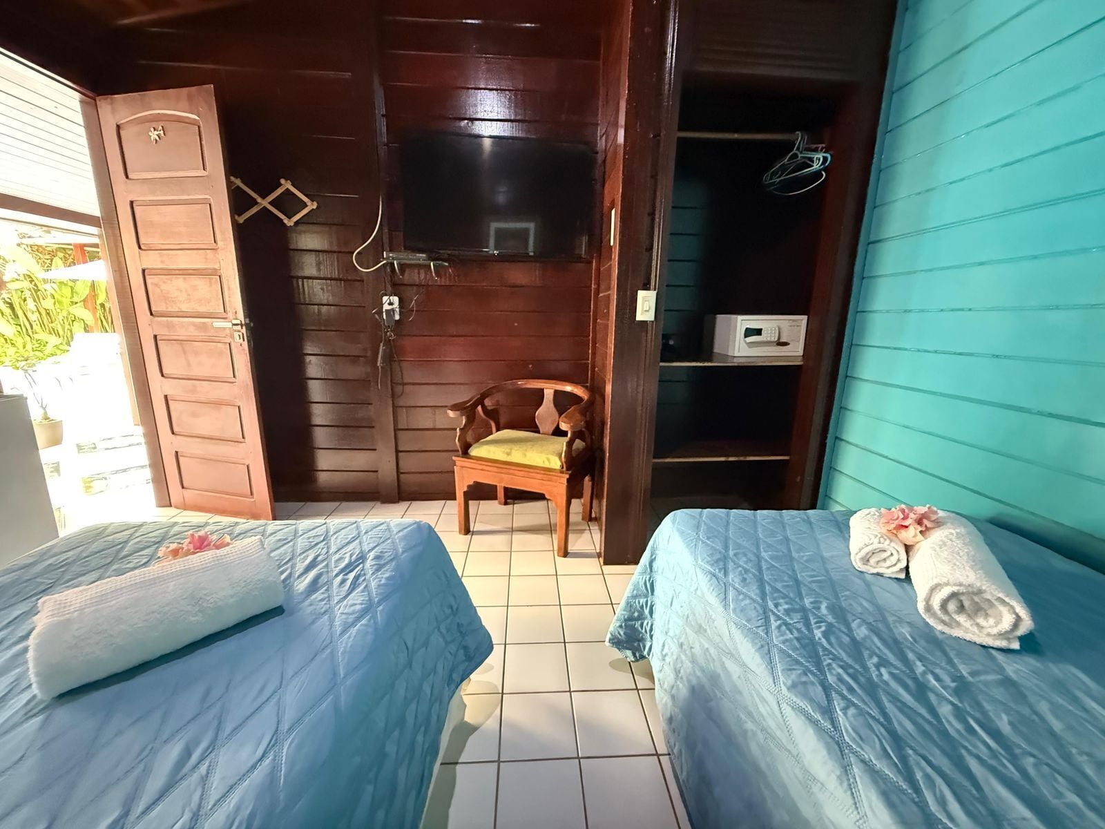 Ein Zimmer mit zwei Betten, einem Holzstuhl, einem Fernseher und einer Mikrowelle.