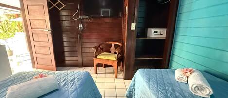 A room with two beds, a wooden chair, a TV, and a microwave.