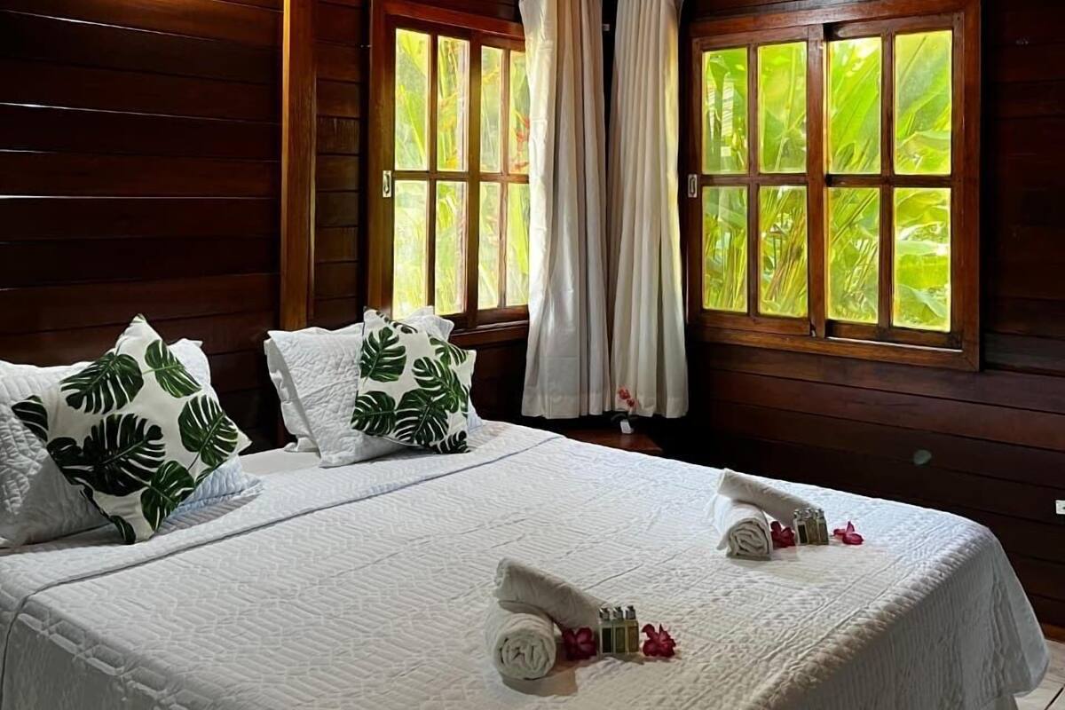 A wooden-paneled room with a bed, curtains, and windows.