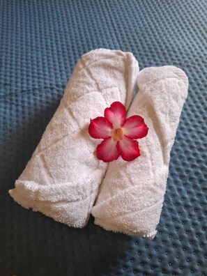 Zwei weiße Handtücher mit einem roten Blumenmuster auf einer blauen, strukturierten Oberfläche.