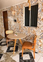 Un comedor con una mesa redonda y dos sillas, una ventana con cortinas y una pared con baldosas decoradas.