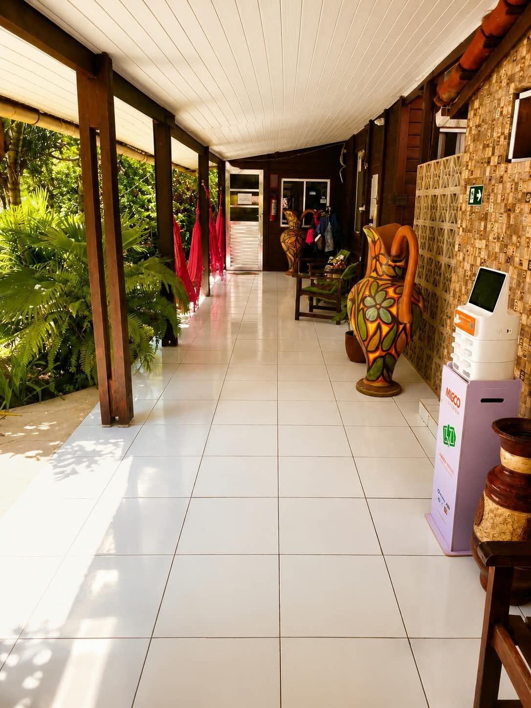 A corridor with a tiled floor, wooden pillars, and a wall with a patterned design.
