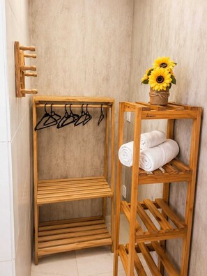 Un mueble de madera con varios compartimentos, que incluye un tendedero y una sección para toallas enrolladas.