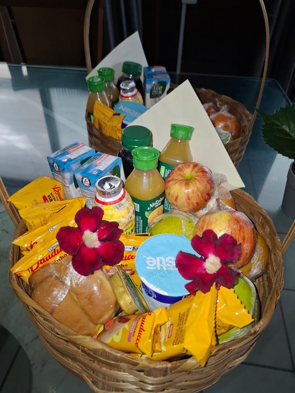 A breakfast basket with bread, butter, jam, and a bottle of juice.