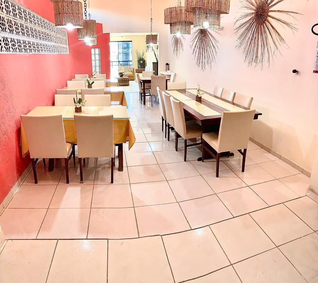 Un comedor con varias mesas y sillas, una escalera que sube a un nivel superior y adornos en las paredes.
