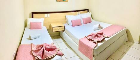 A hotel room with two beds, each with pink and white bedding, a small bedside table, and a colorful abstract painting on the wall.