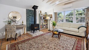 A cozy living room with a sofa, a chair, a bookshelf, a fireplace, and a large window.