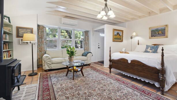 A cozy room with a wooden bed, a sofa, a small table with a plant, and a bookshelf.