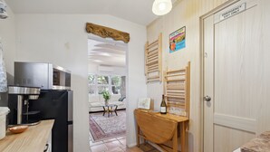A kitchen with a refrigerator, microwave, and a wooden table with a wine bottle and glasses.