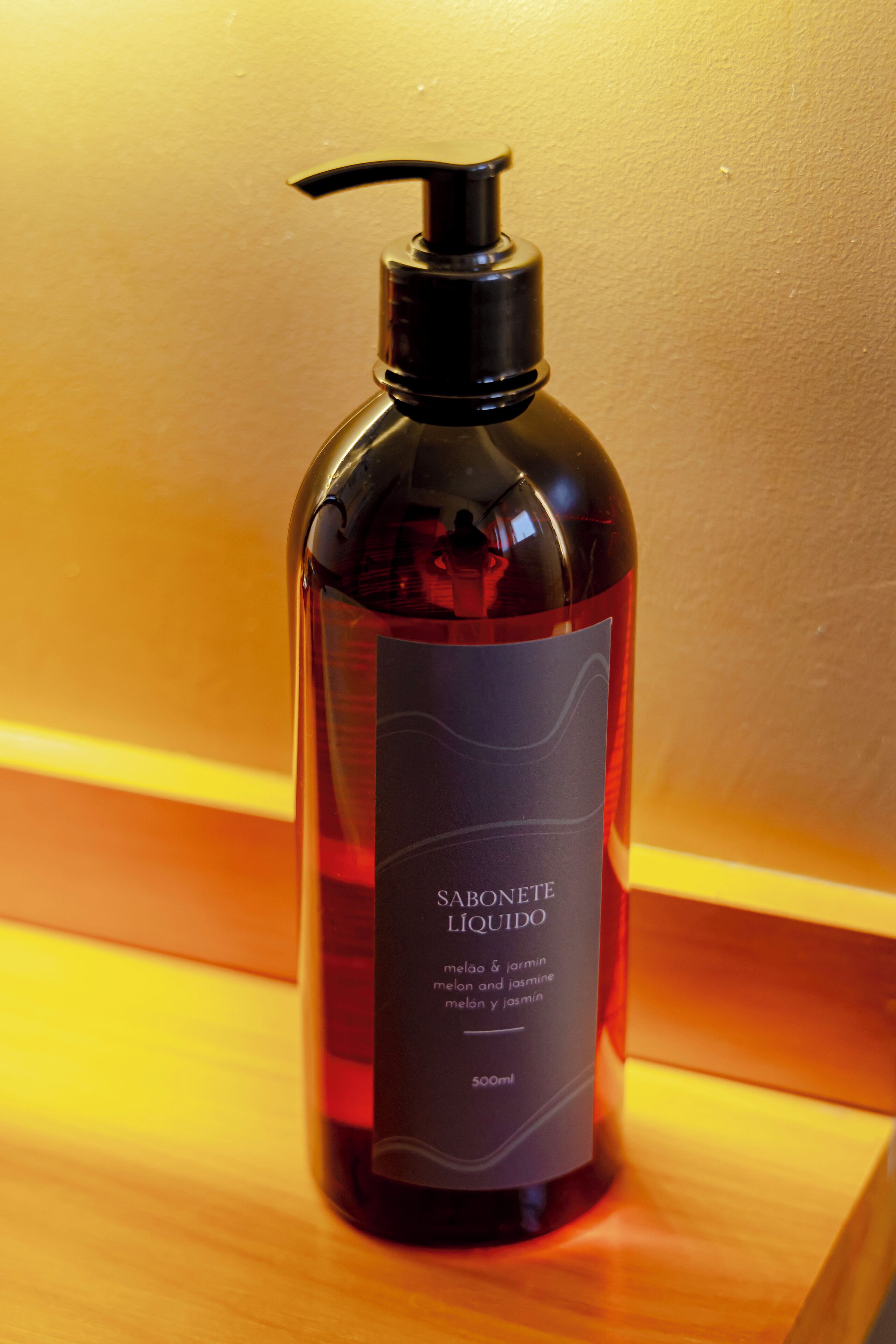 A bottle of soap with a pump dispenser on a wooden surface.