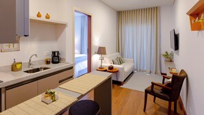 A modern kitchen with a built-in oven, a coffee maker, and a small dining area with a table and chairs. - Zur Suítes (Campos do Jordão)