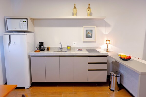 Una cocina moderna con microondas integrado, cafetera, lavaplatos y un frutero sobre la encimera.