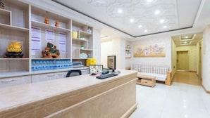 A reception area with a marble counter, shelves with decorative items, a sofa, and a painting on the wall. - Yanji Ruifeng Hotel (Yanji)