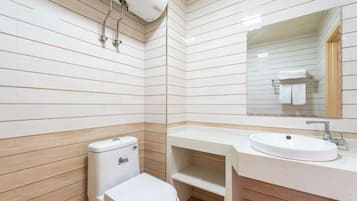 Une salle de bain équipée de toilettes, d’un lavabo, d’un miroir et de murs recouverts de panneaux en bois.