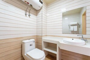 Ein Badezimmer mit Toilette, Waschbecken, Spiegel und Wandverkleidungen aus Holz.