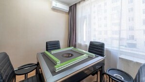 A hotel room with a table, four chairs, an air conditioning unit, and a window with curtains. - Yanji Ruifeng Hotel (Yanji)