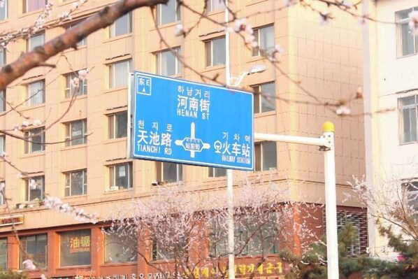 A blue directional sign with text in a foreign language, mounted on a pole. - Yanji Ruifeng Hotel (Yanji)