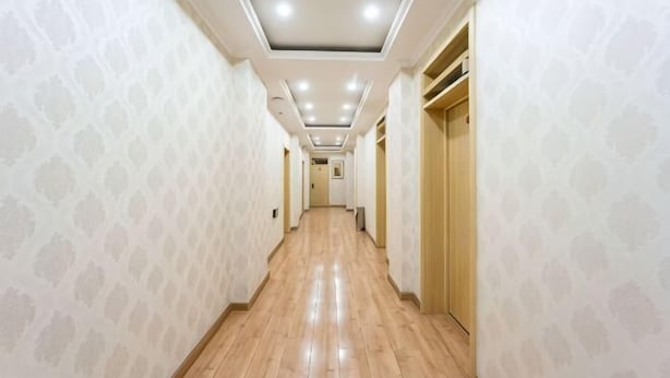 A hallway with patterned wallpaper, wooden flooring, and recessed ceiling lights. - Yanji Ruifeng Hotel (Yanji)