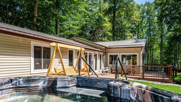 A wooden deck with a hot tub, a swing set, and a covered seating area. - Private Hilltop Retreat | Hot Tub & 15 Min to Nashville3BR, 3.5 BA (Nashville)
