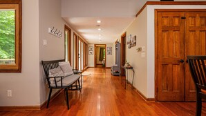 A hallway with wooden flooring, a bench, and a door. - Private Hilltop Retreat | Hot Tub & 15 Min to Nashville3BR, 3.5 BA (Nashville)