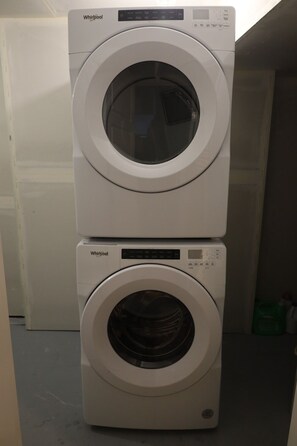Two stacked Whirlpool front-loading washing machines in a laundry room. - Cozy entire 2 bedroom apartment located in the heart of Mahogany. Pet friendly. (Calgary)