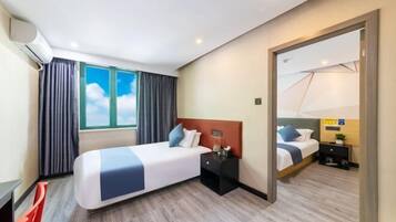 A hotel room with a bed, a nightstand, a mirror, and a window with curtains.