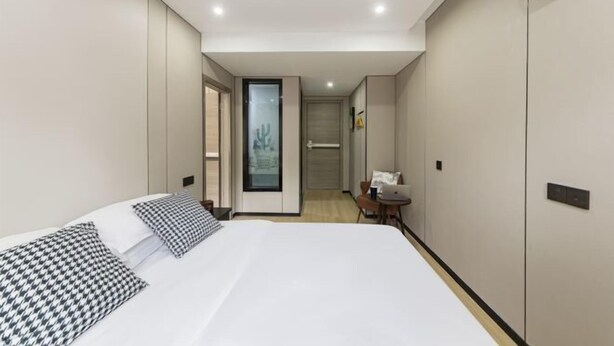 Ein modernes Hotelzimmer mit einem großen Bett, einem Schreibtisch und Blick durch eine Tür.